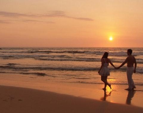 A couple walking on the beach at sunset 